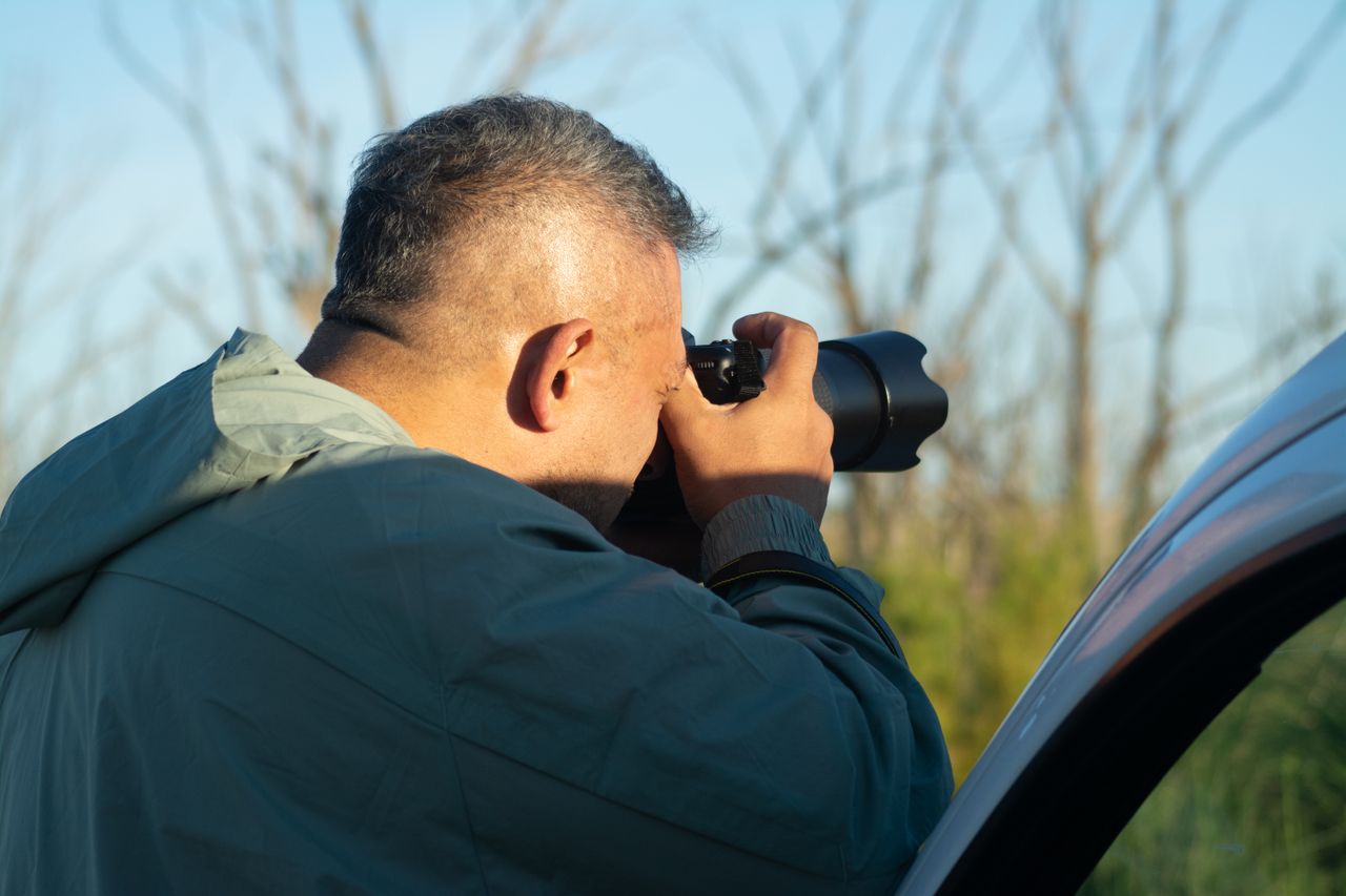 Photographer taking photos outdoors with telephoto lens during the day.