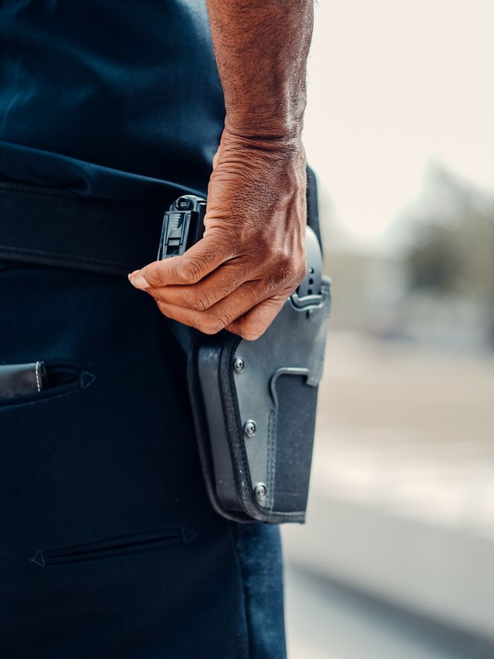 Home A police officer's hand gripping the holster of a handgun, symbolizing readiness and security.